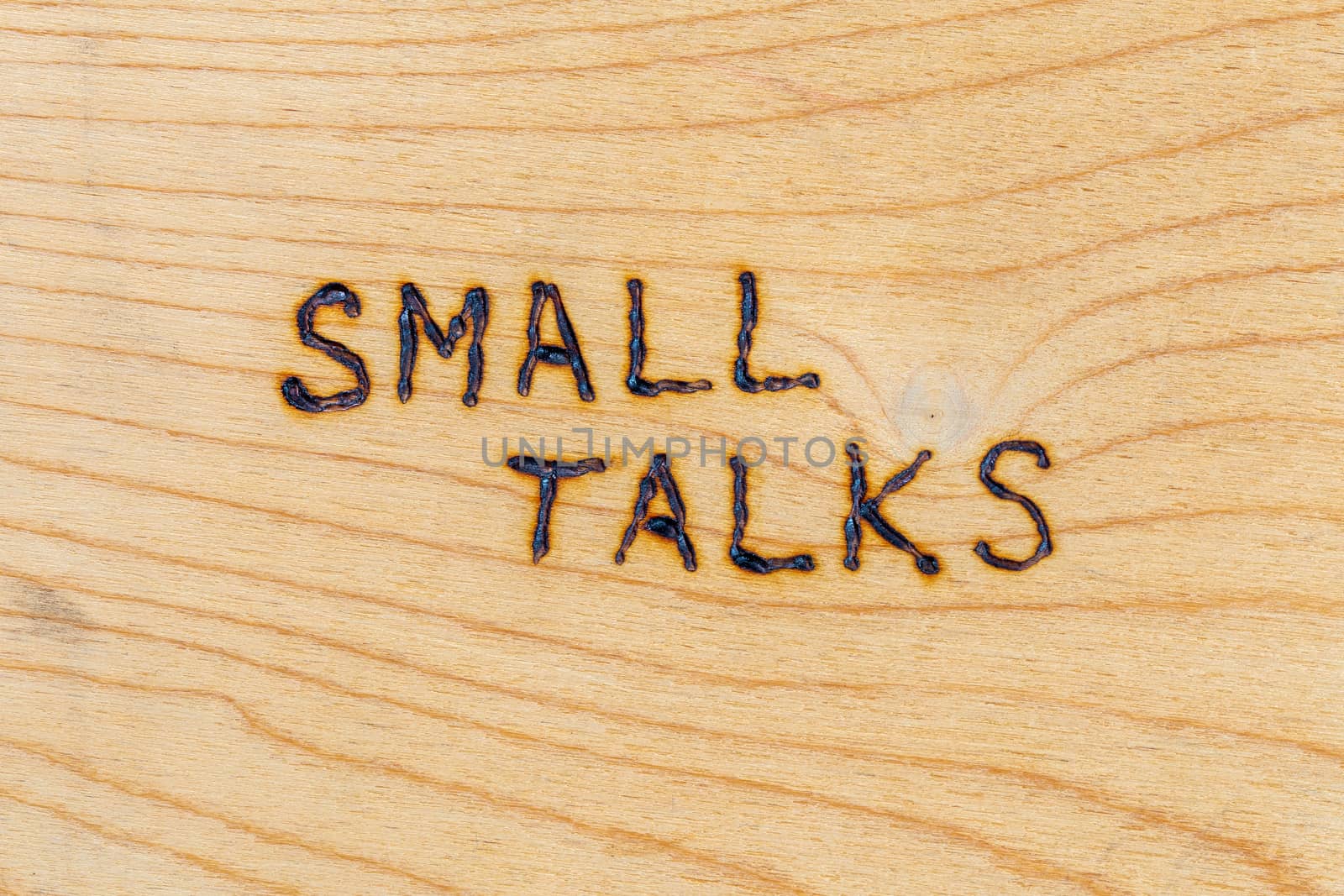 the words small talks handwritten with woodburner on flat plywood surface in directly above perspective