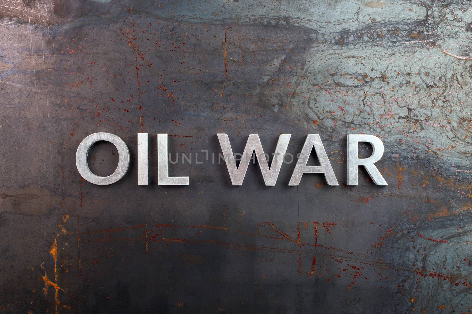 words oil war laid in line with silver metal letters on rusted heavy hot rolled uncoated steel sheet surface - directly above in flat lay composition