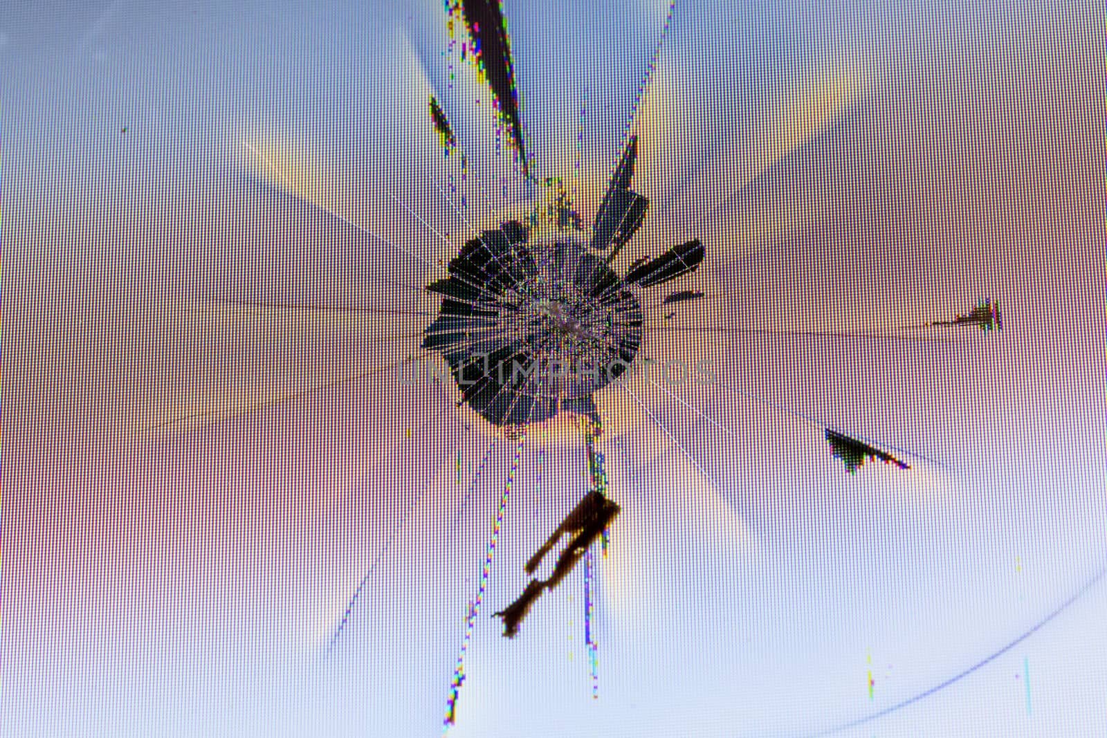 close-up view of physically damaged lcd screen surface with impact spot, radial cracks, pixel grid leakage and discoloration.