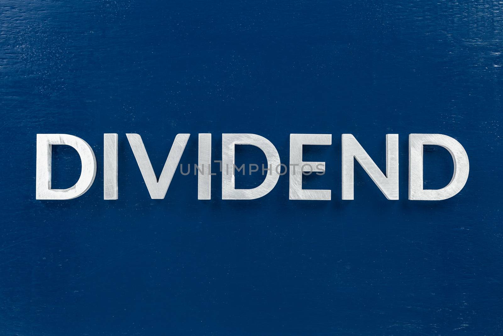 the word dividend laid with brushed metal letters on dark blue background by z1b