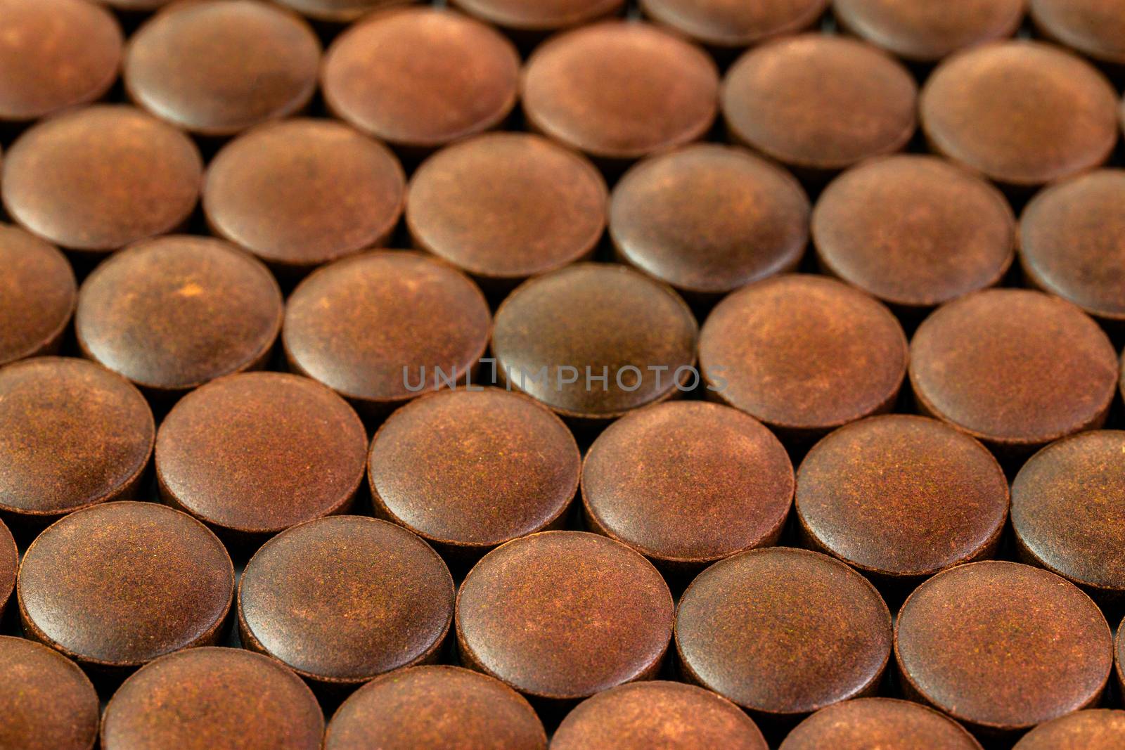 close-up background of many orange organic powder tablets laid tight in one layer on flat surface.