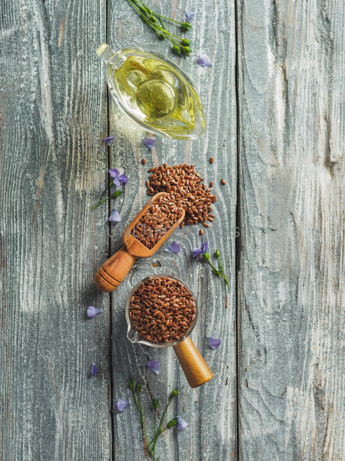 Flax seeds and flax oil. Brown linen seeds and flaxseed oil on old gray wooden background. Copy space. Top view or flat lay. Vertical.