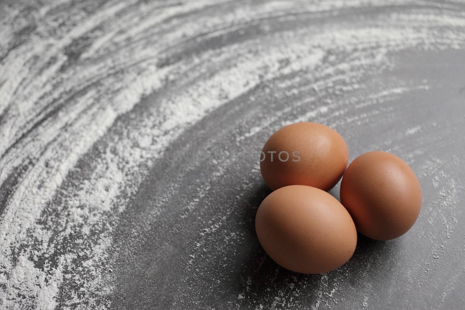 Three Chicken egg and flour on grey background table. Eggs by selinsmo