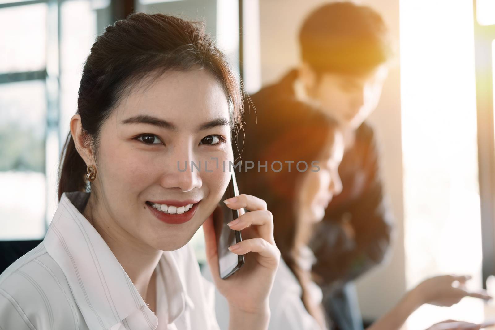 Young asian businesswoman beautiful charming smiling and talking on the mobile phone in meeting room by nateemee