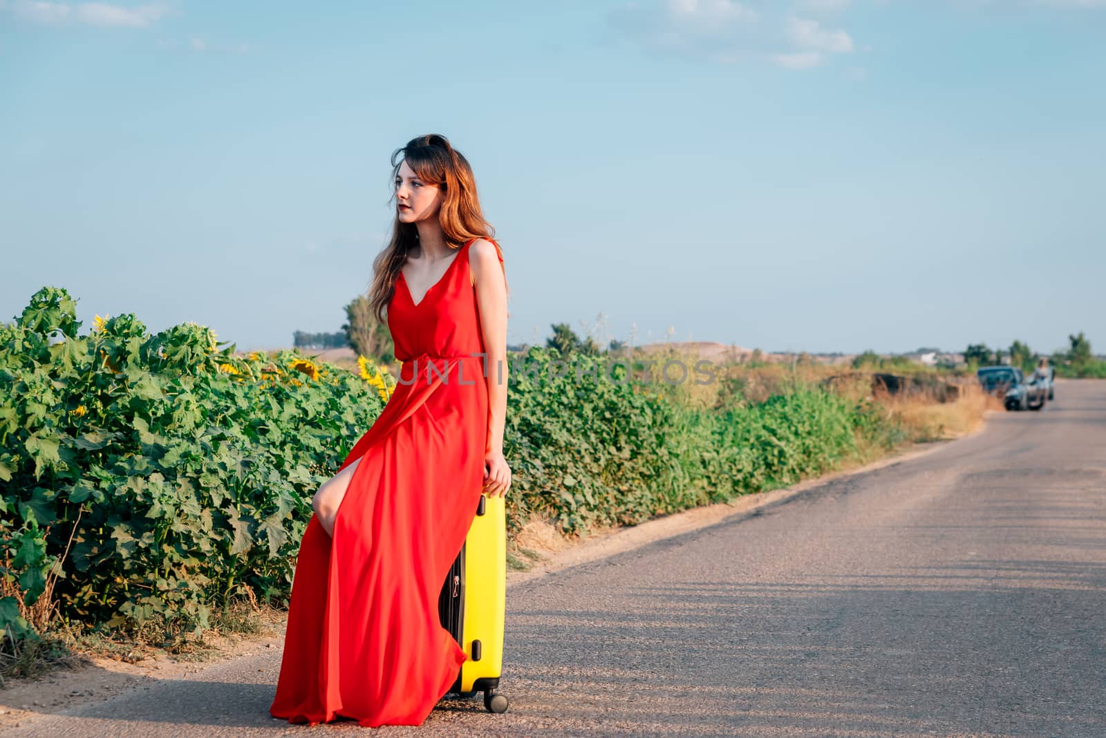 sad woman sitting in a suitcase on the road