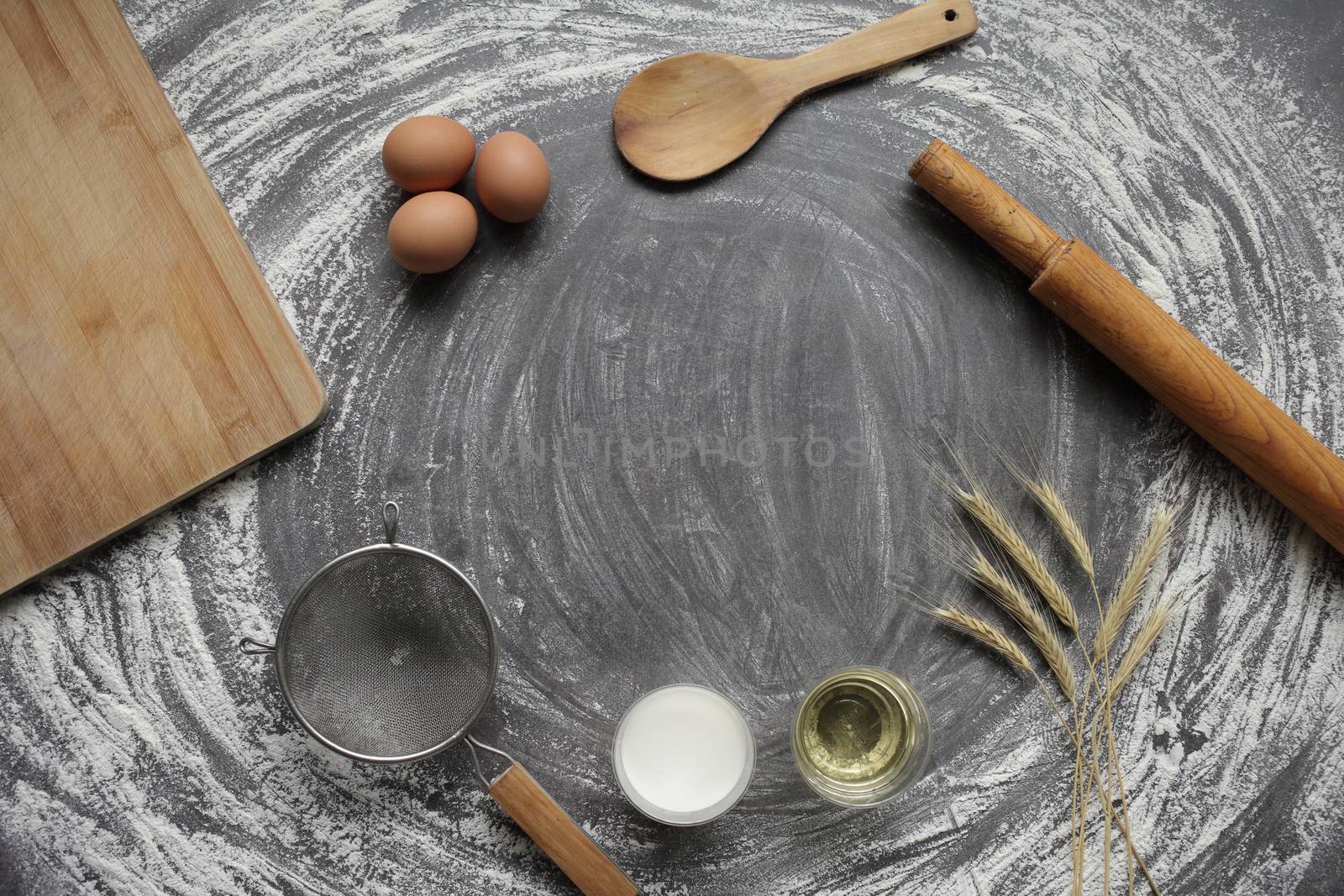 Egg, flour, olive oil, milk, wheat ears, kitchen tool on gray table background. by selinsmo