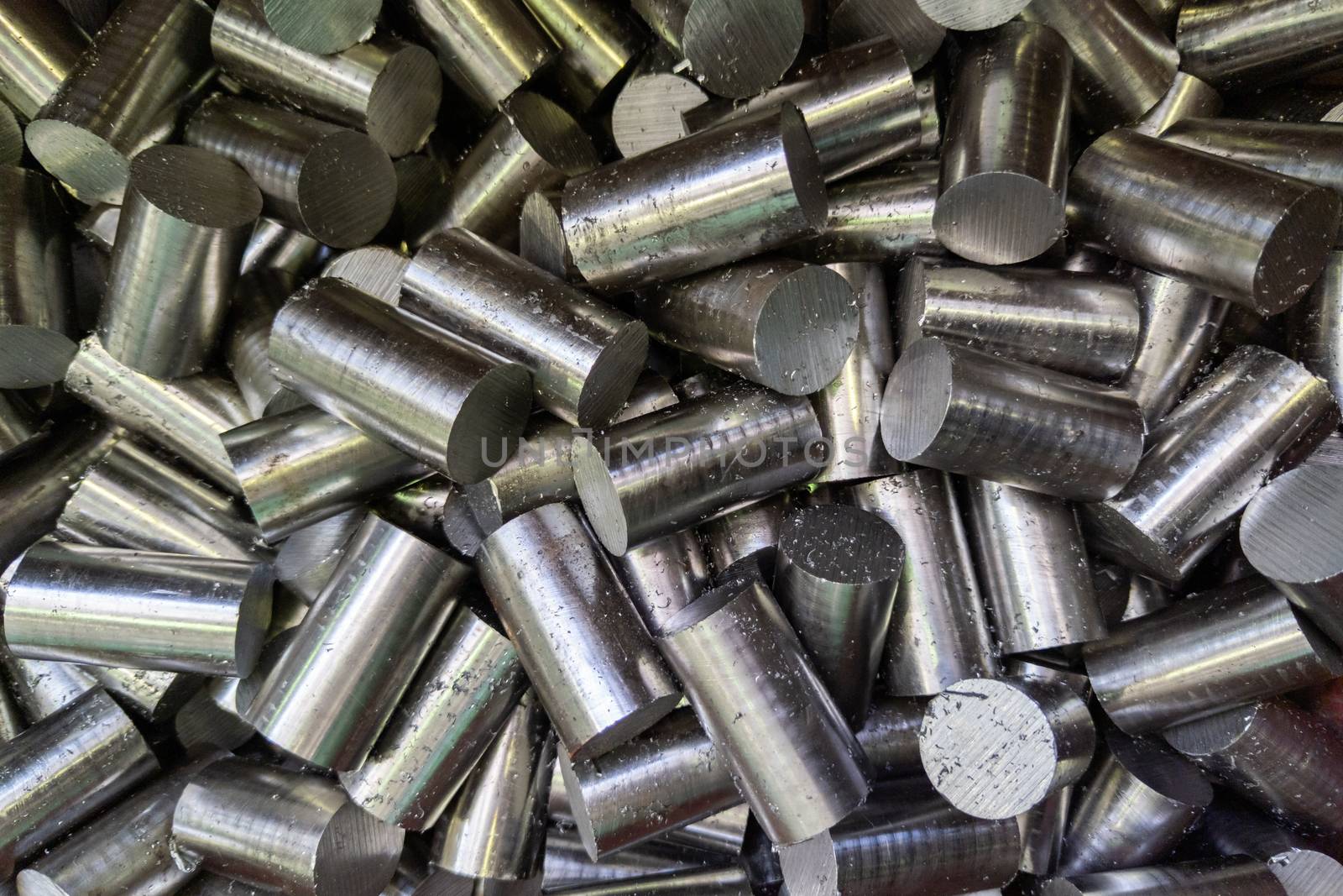 pile of saw cutted stainless steel rods with metal sawdust - closeup with selective focus