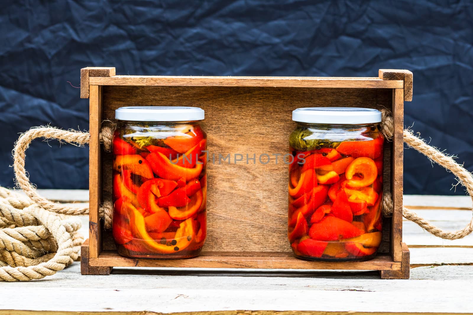 Wooden crate with glass jars with pickled red bell peppers.Prese by vladispas