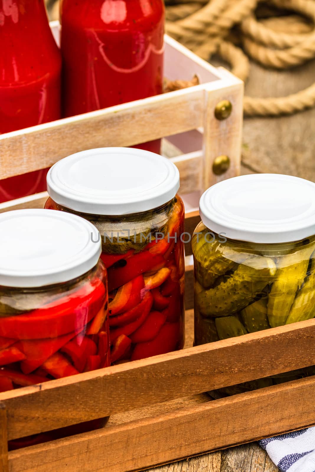 Wooden crate with glass jars with pickled red bell peppers and p by vladispas