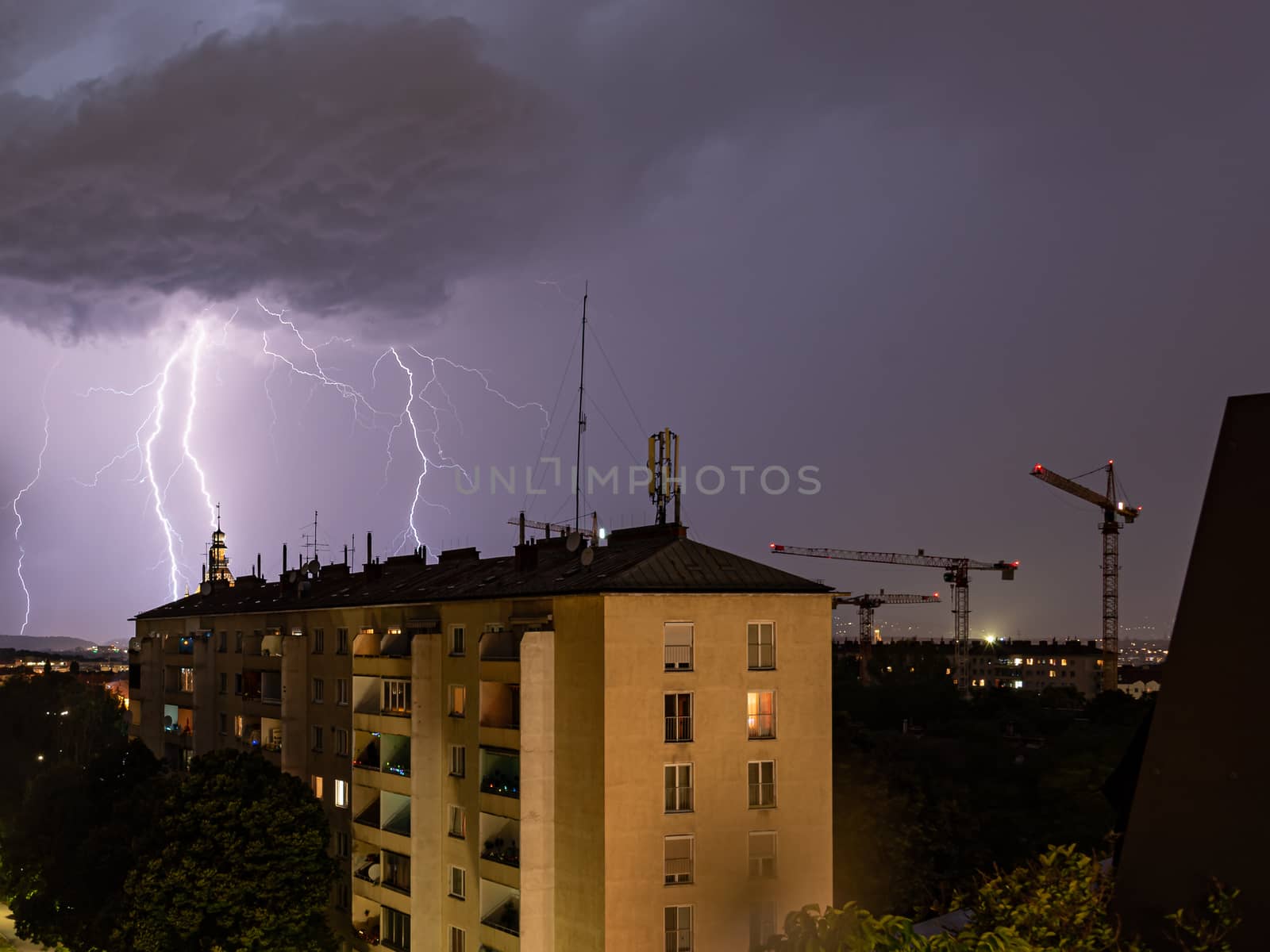 Violent summer thunderstorm with enormous lightning over the Wienerberg City in Vienna with construction cranes on the right side of the picture by Umtsga