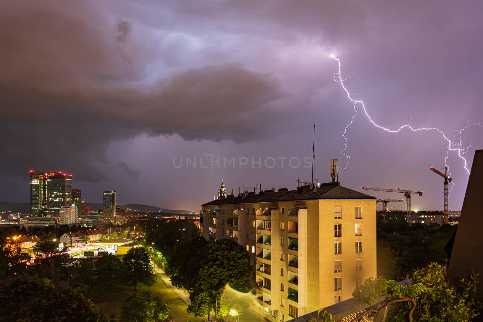 Violent summer thunderstorm with enormous lightning over the Wienerberg City in Vienna with construction cranes on the right side of the picture by Umtsga