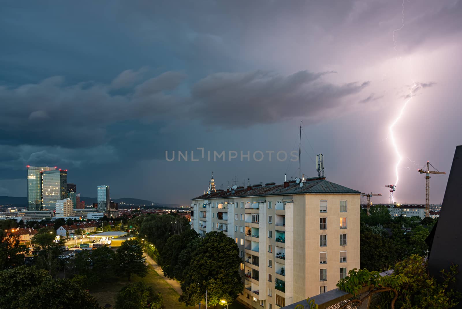 Violent summer thunderstorm with enormous lightning over the Wienerberg City in Vienna with construction cranes on the right side of the picture by Umtsga