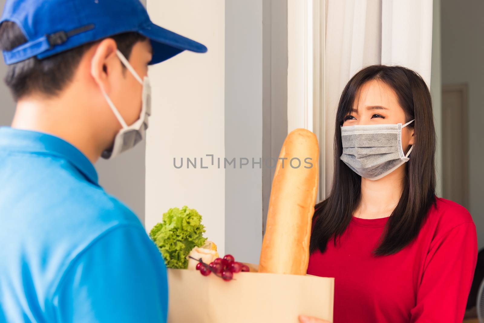 Delivery man wear protective face mask making grocery giving fre by Sorapop