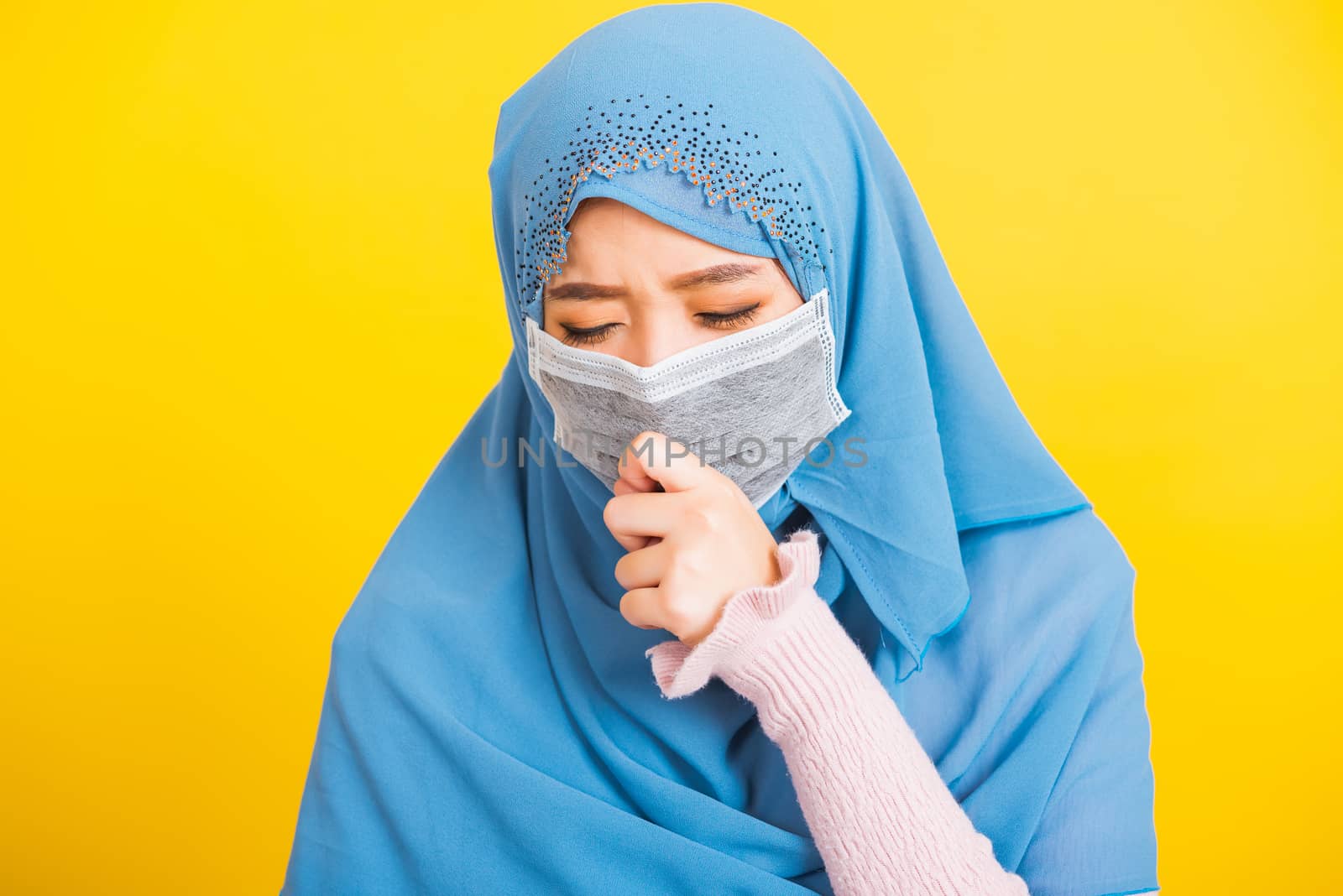 Asian Muslim Arab, Portrait of happy beautiful young woman religious wear veil hijab she wearing protective face mask, outbreak coronavirus use hand close mouth and sneeze, isolated yellow background
