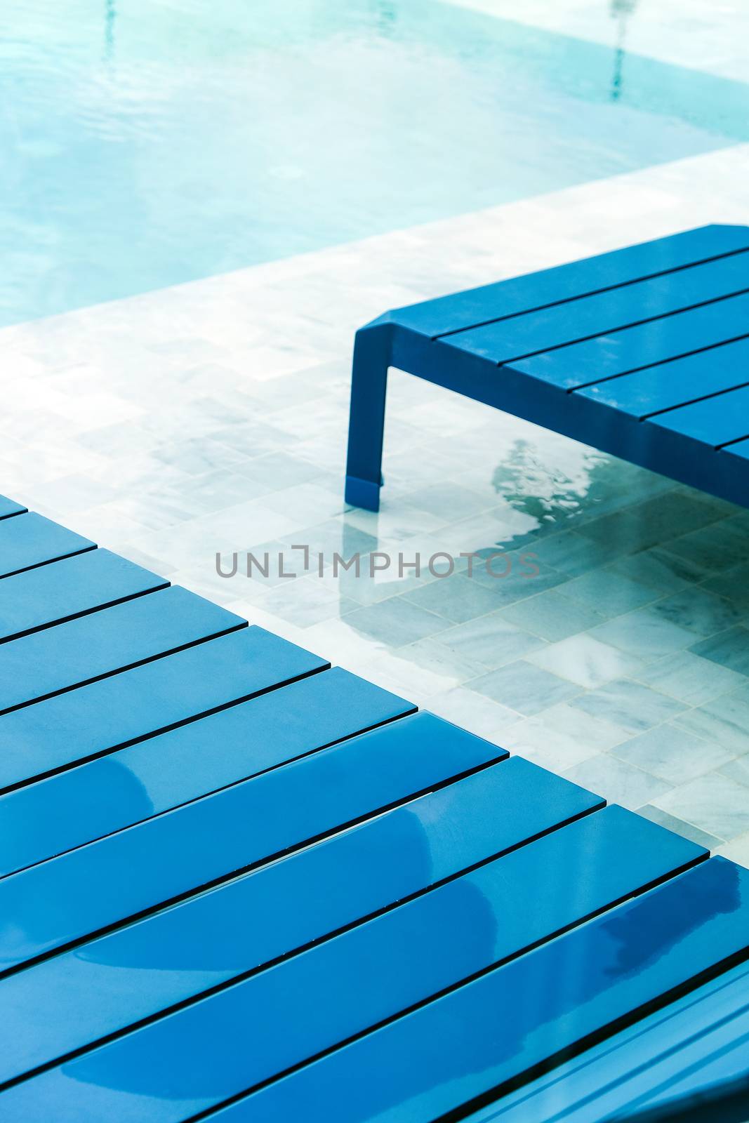 Swimming pool with chaise loungers background by ponsulak