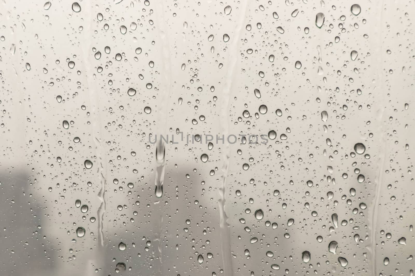 Water rain drops on window glass surface with cloudy background for your design. Natural Pattern of raindrops on glass background. Copy space, No focus, specifically.