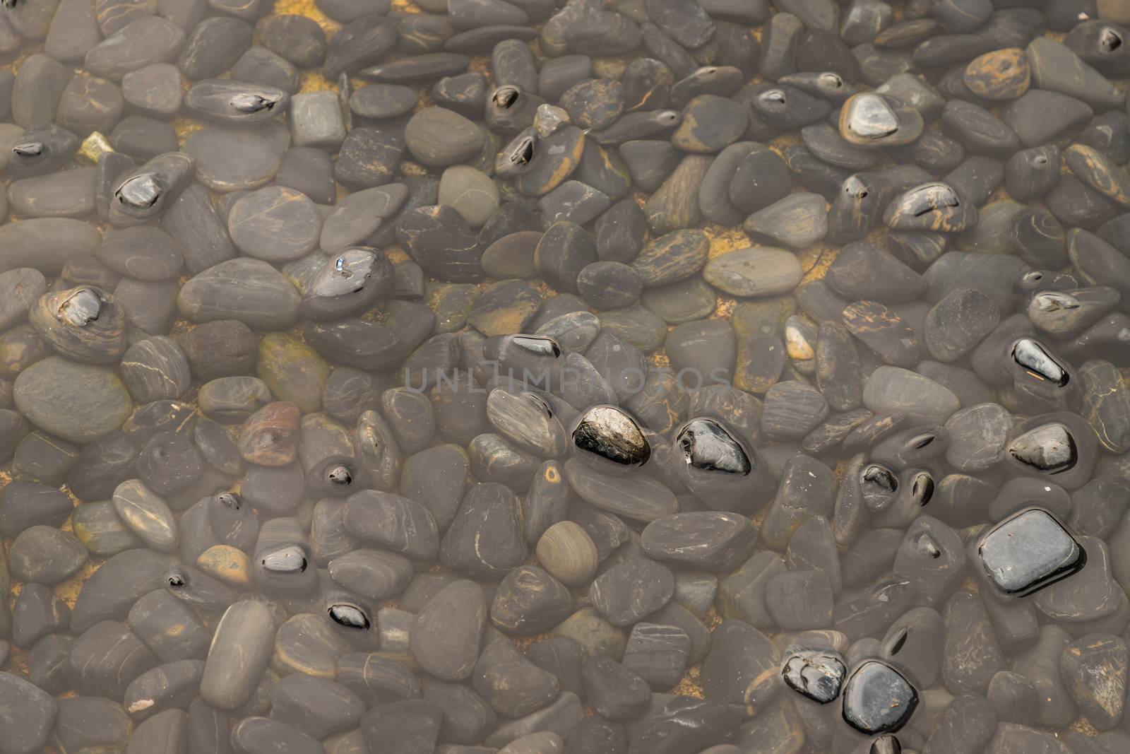 Stones and rocks pile and texture of black, gray and brown under the water as nature background. Excellent concept for any design. Rocks in transparent water. No focus, specifically.