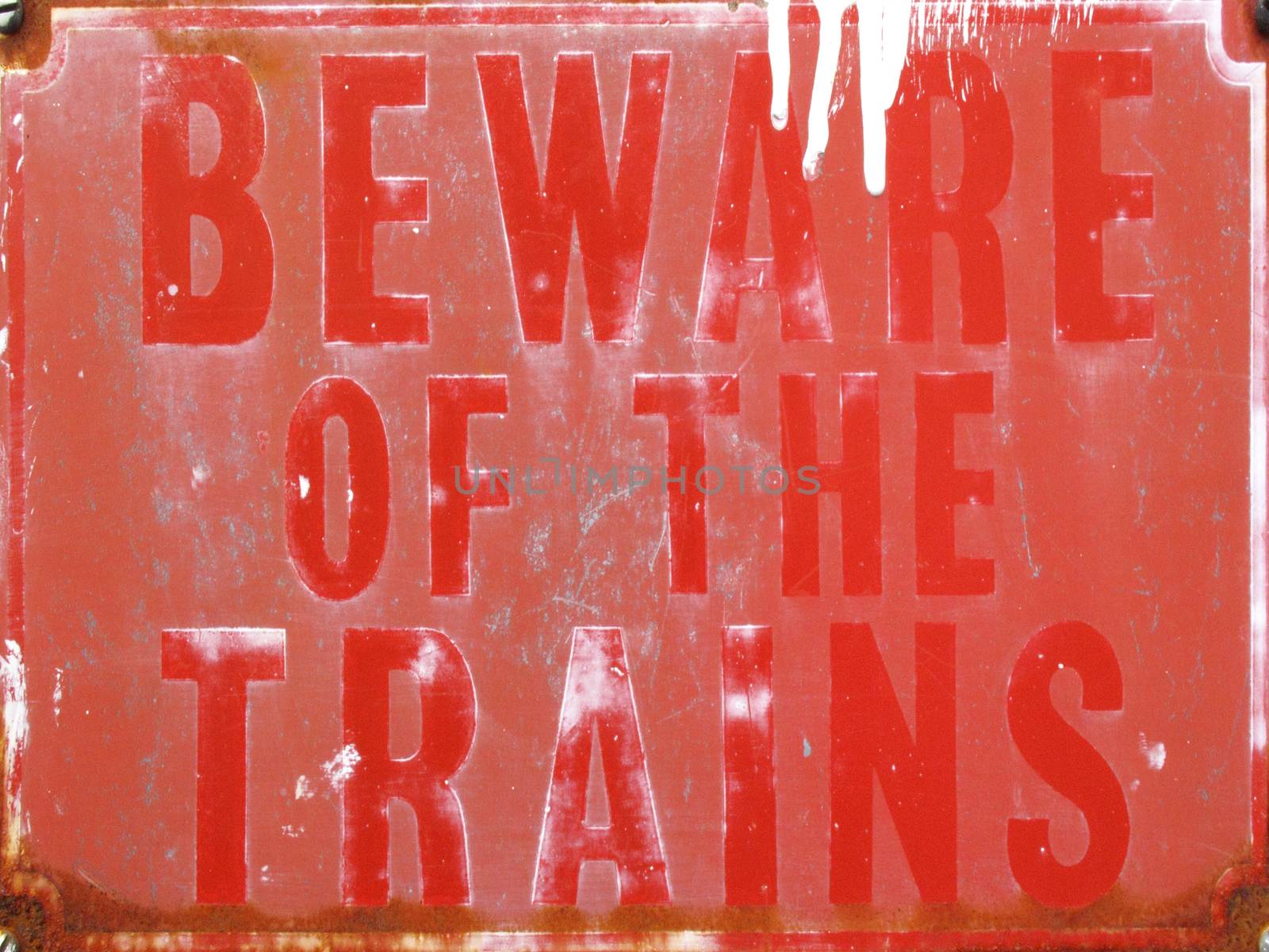 Old vintage red retro distressed railway enamel metal train sign with text beware of the trains stock photo