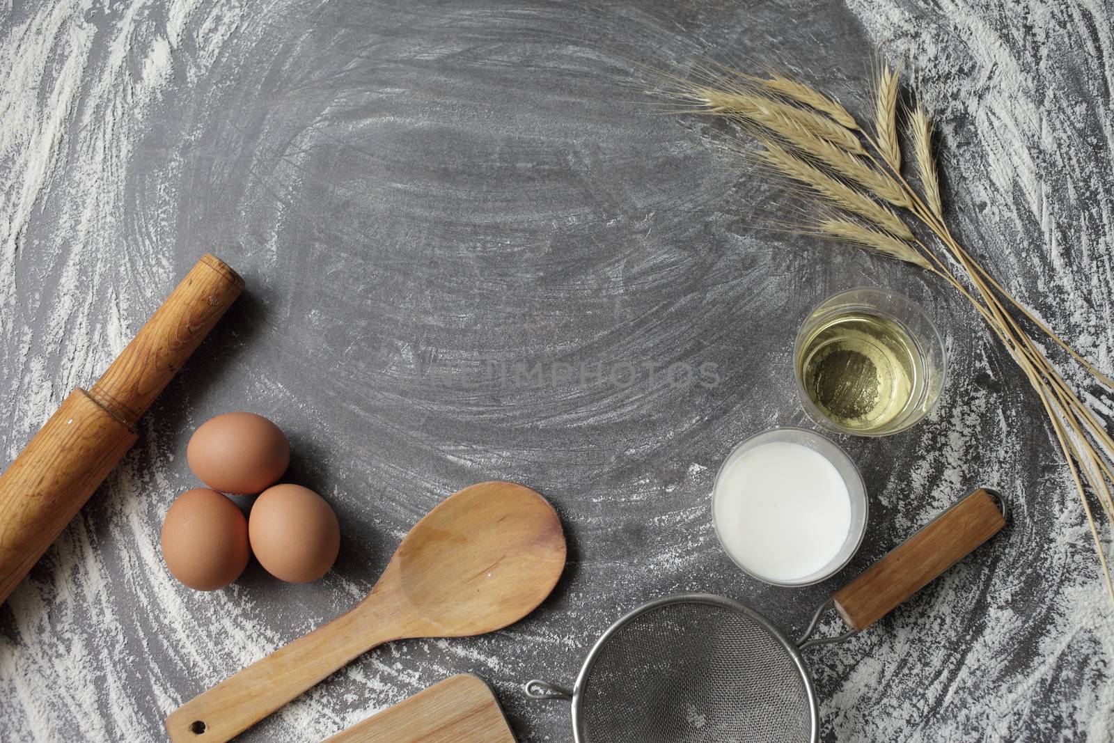 Egg, flour, olive oil, milk, wheat ears, kitchen tool on gray table background. by selinsmo