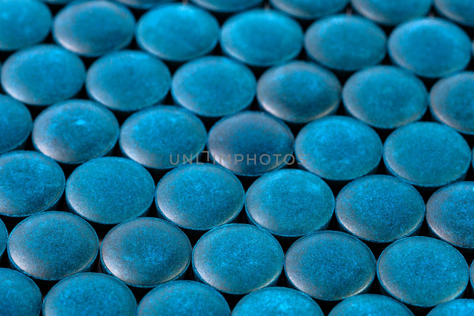 close-up background of many blue organic spirulina tablets laid tight in one layer on flat surface by z1b