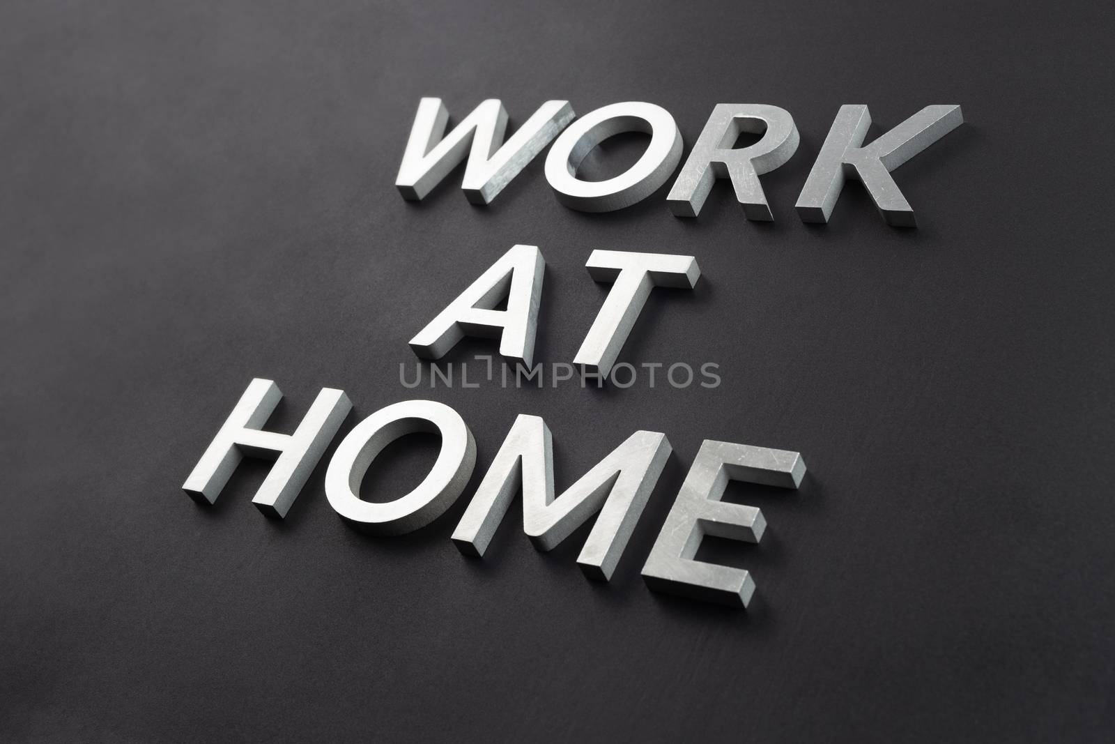 the words work at home laid with silver metal letters on matte black background in diagonal perspective by z1b