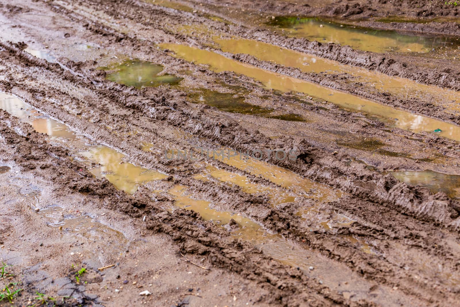 dirty clay mud road with puddles and tire tracks - closeup with selective focus, diagonal composition by z1b