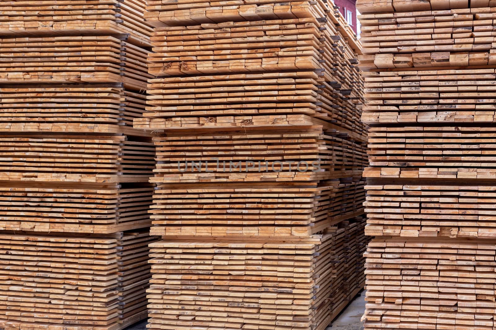 Large stacks of wooden planks full frame background with perspective. Woodwork industrial storage.