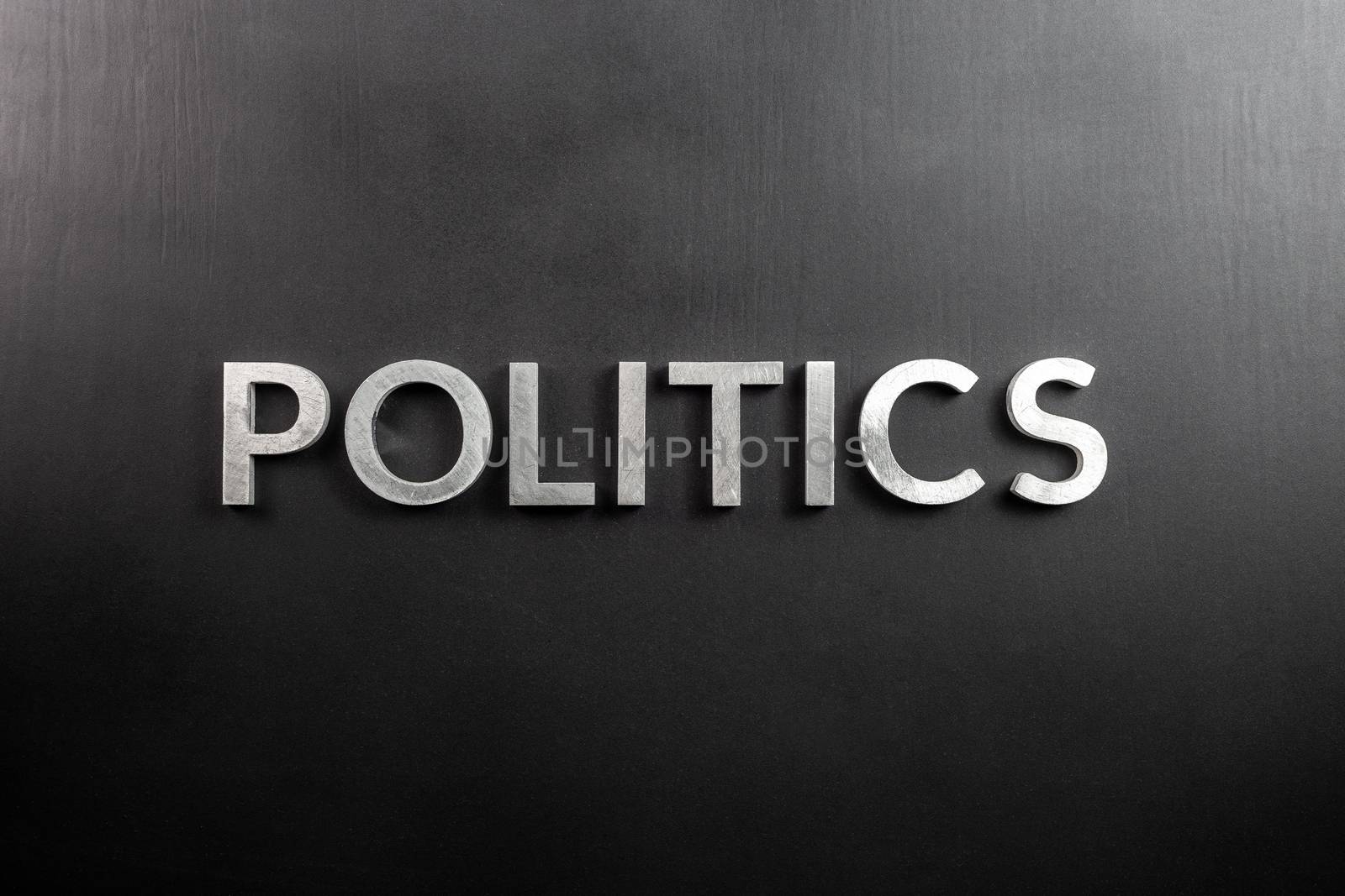the word politics laid with aluminium letters over matte black flat surface - directly above perspective by z1b