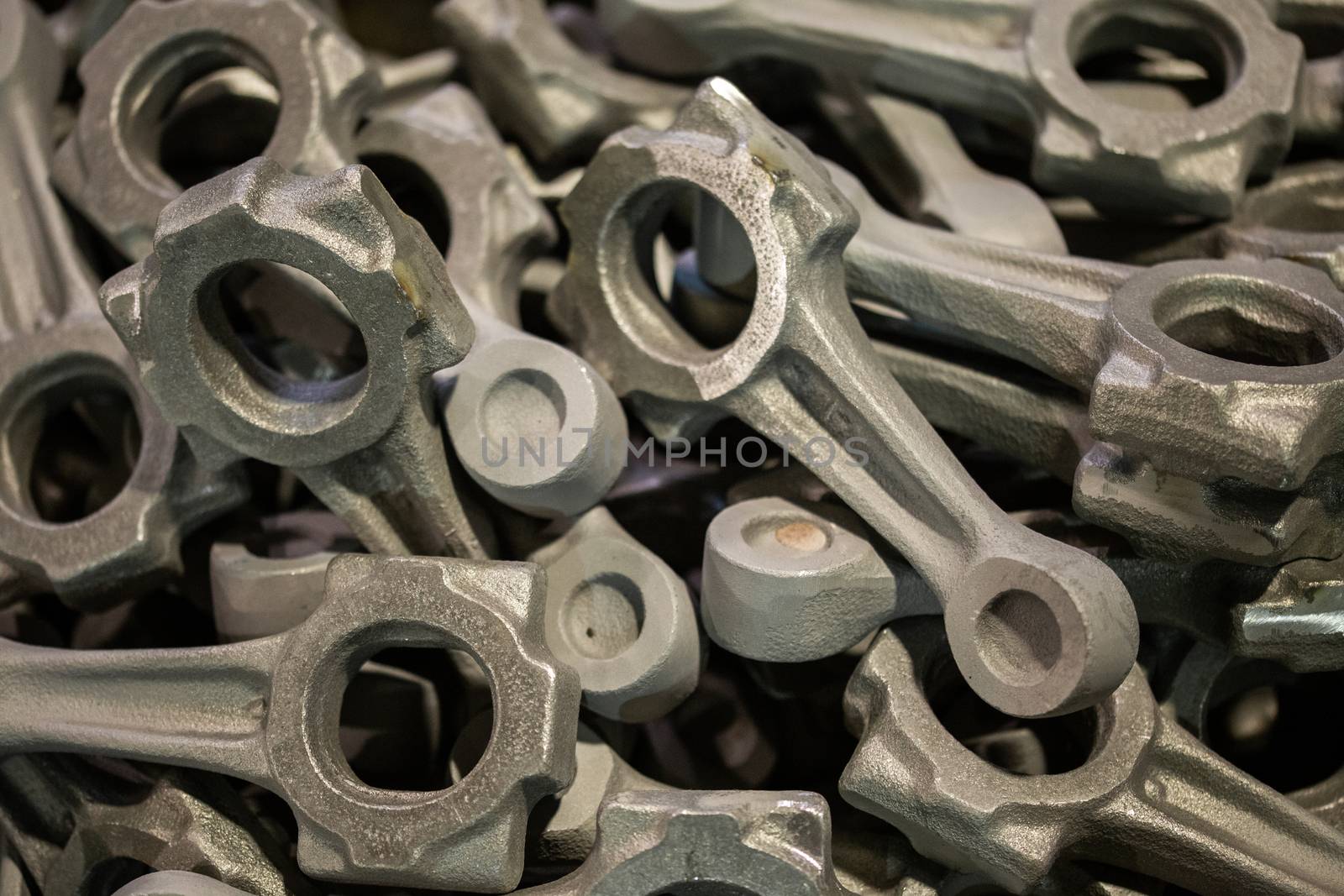 pile of crankshaft connecting rod forgings after cooling and shot blasting operations, close-up with selective focus and background blur