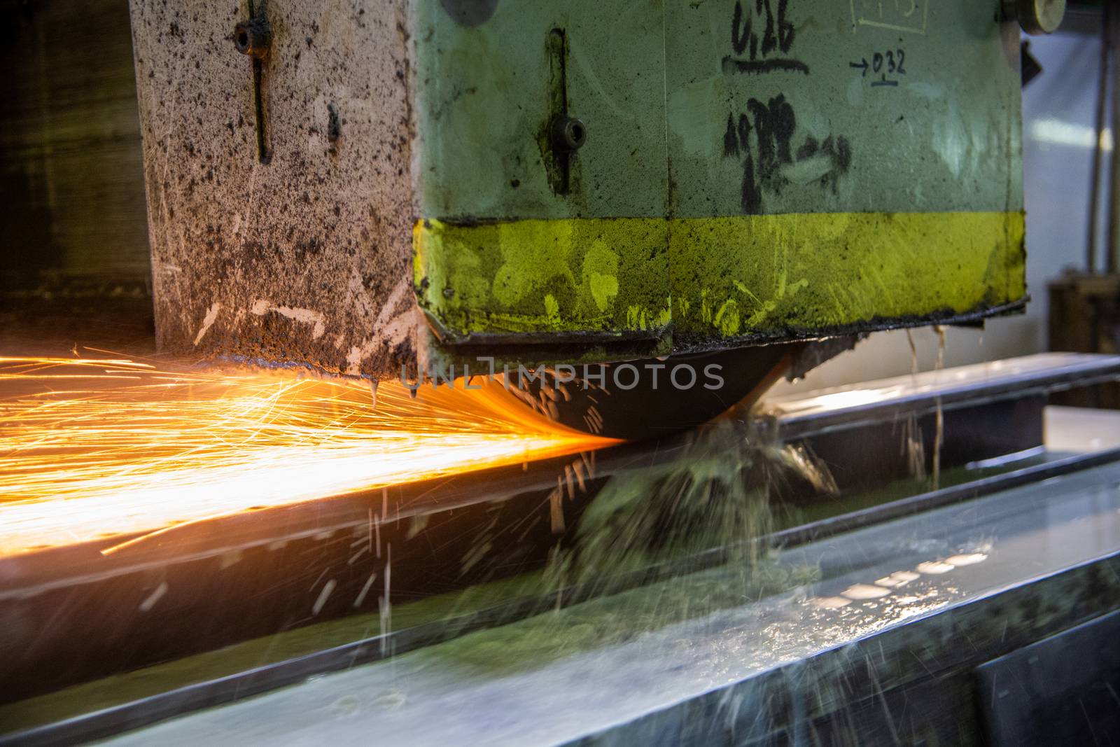 a process of flat surface grinding with a lot of sparks and liquid cooling indoors at metalworking shop, old factory equipment at work