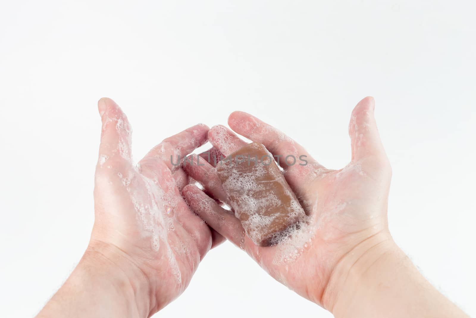 a wet piece of brown tar soap in human hands on white background.