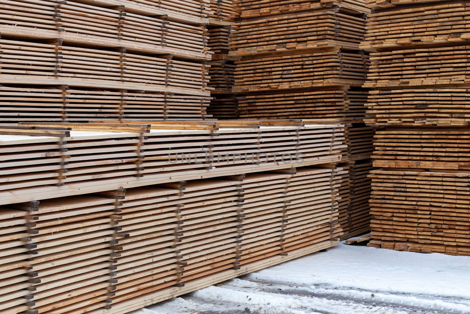 Large stacks of wooden planks background with selective focus and linear perspective. Winter woodwork industrial storage.