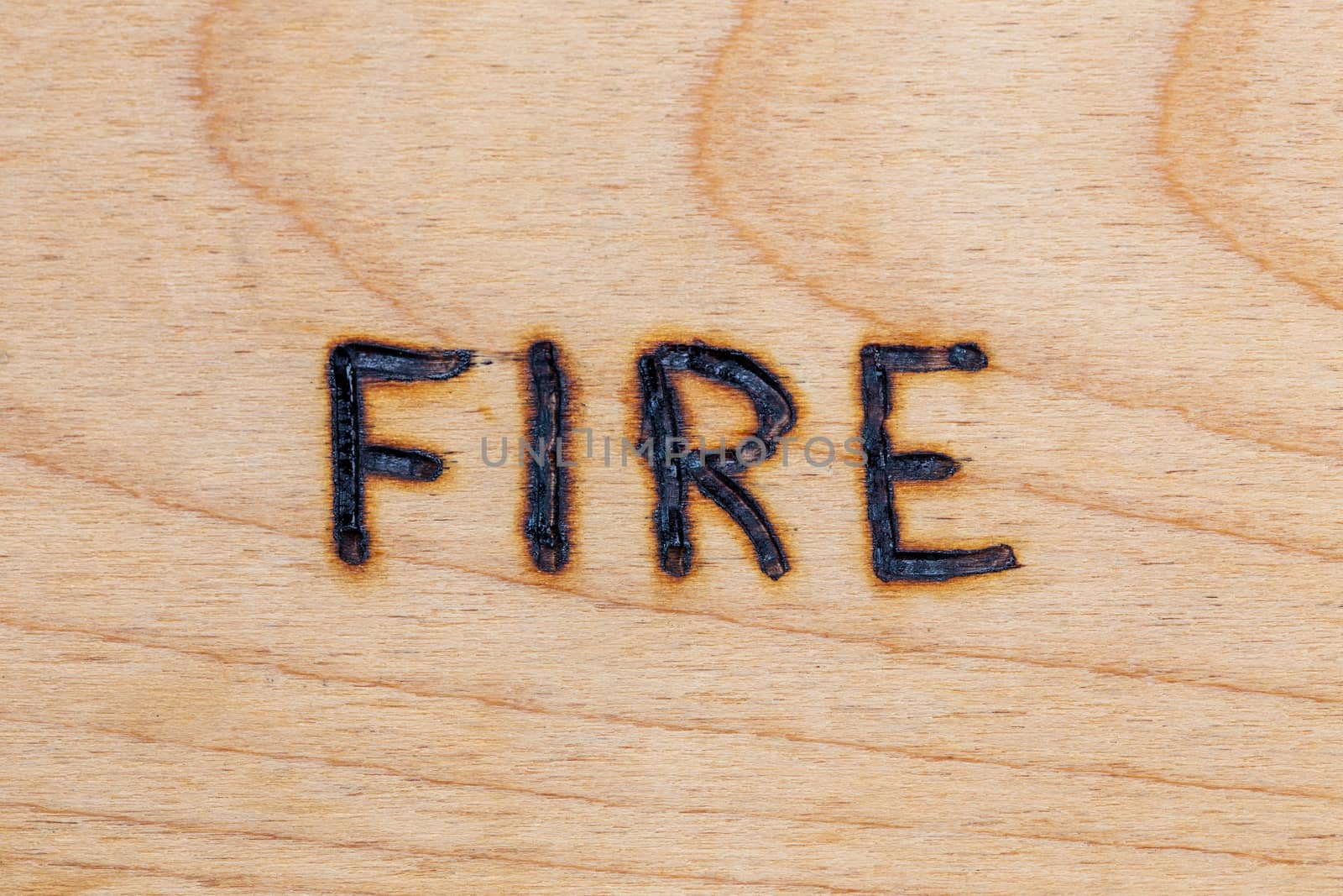 the word fire handwritten on flat wooden surface with electrical woodburner