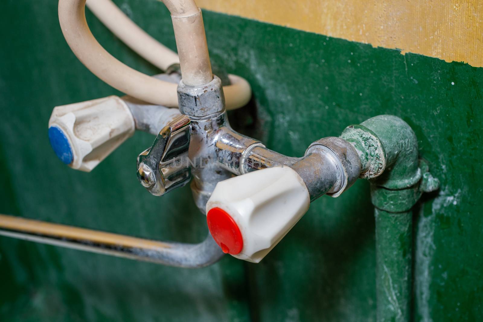 a close-up view of stained old russian chrome water faucet, focus on foreground, blur on background