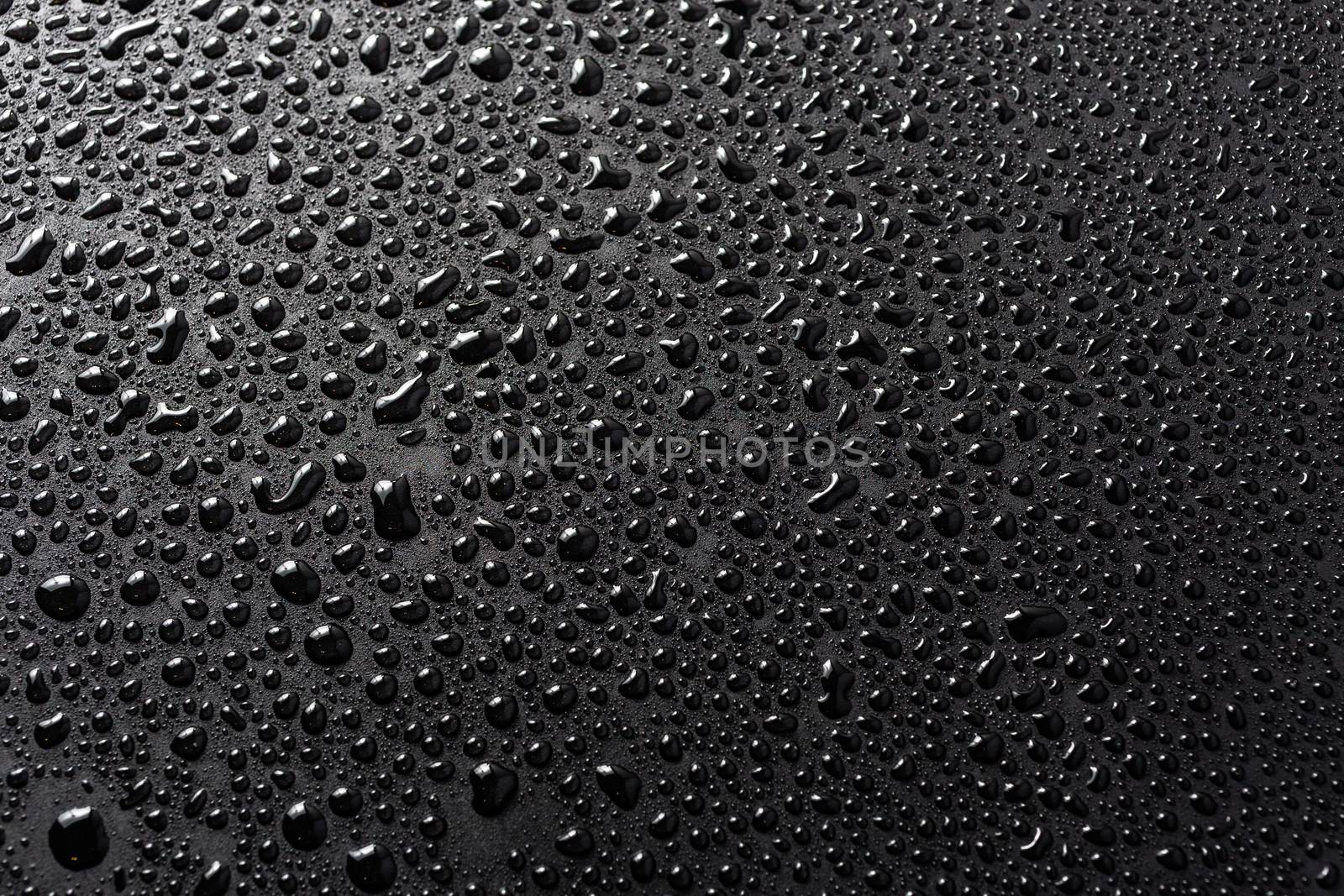 close-up view of water drops on black flat matte surface macro sith selective cous and background blur