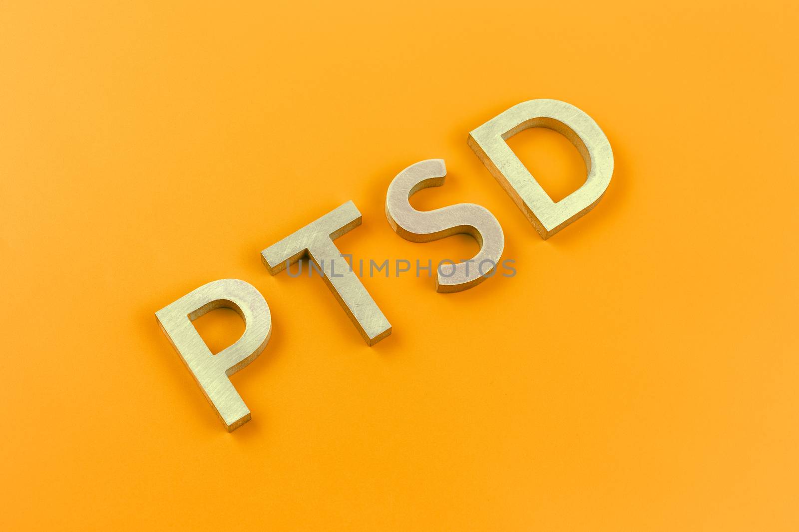 abbreviation PTSD - post traumatic stress disorder - laid with silver metal letters on yellow flat surface in ascending diagonal composition