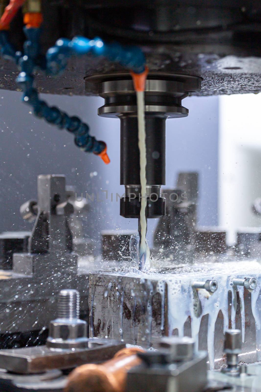 a process of cnc vertical drilling with liquid coolant flow, close-up with selective focus