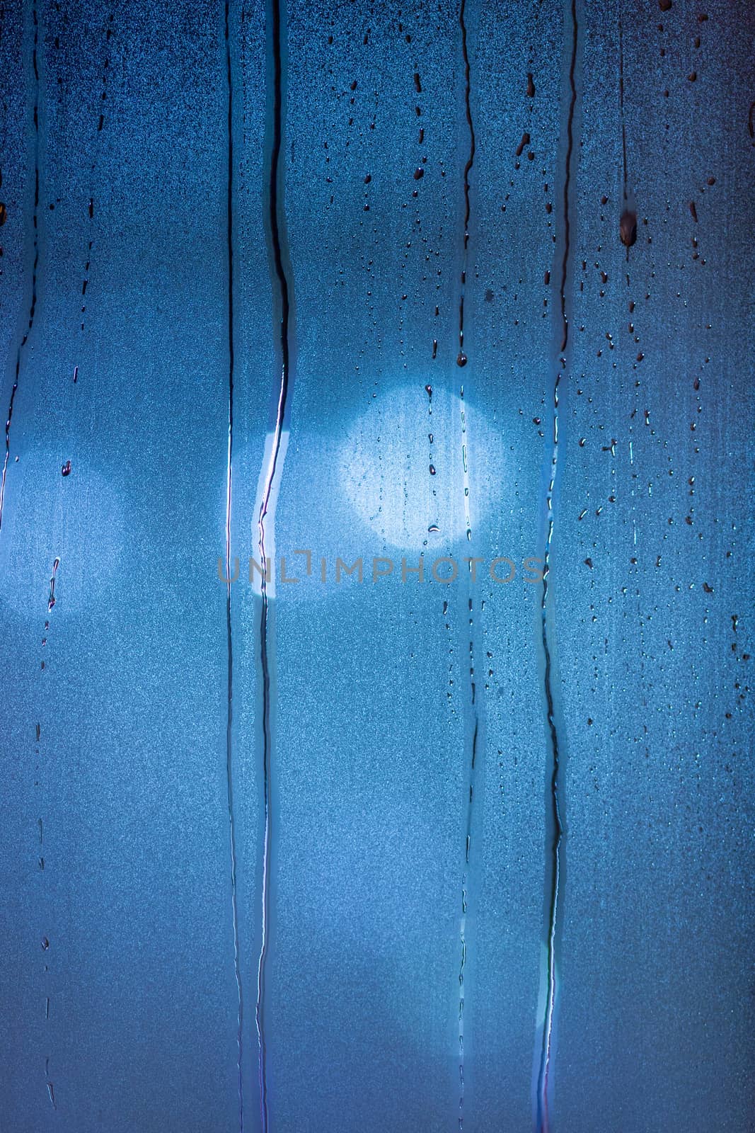 an abstract background of night wet window glass with smudges in blue tone gamma by z1b