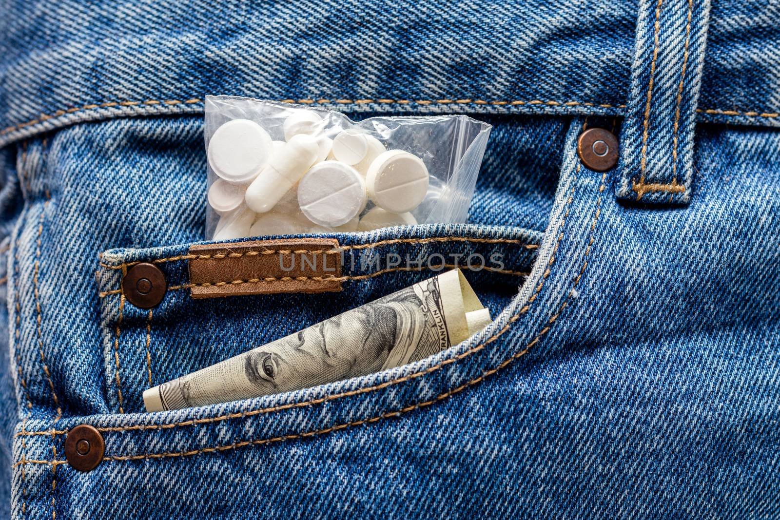 a hundred dollar banknote and pack of white pills sticking out from front pocket of jeans - close-up by z1b