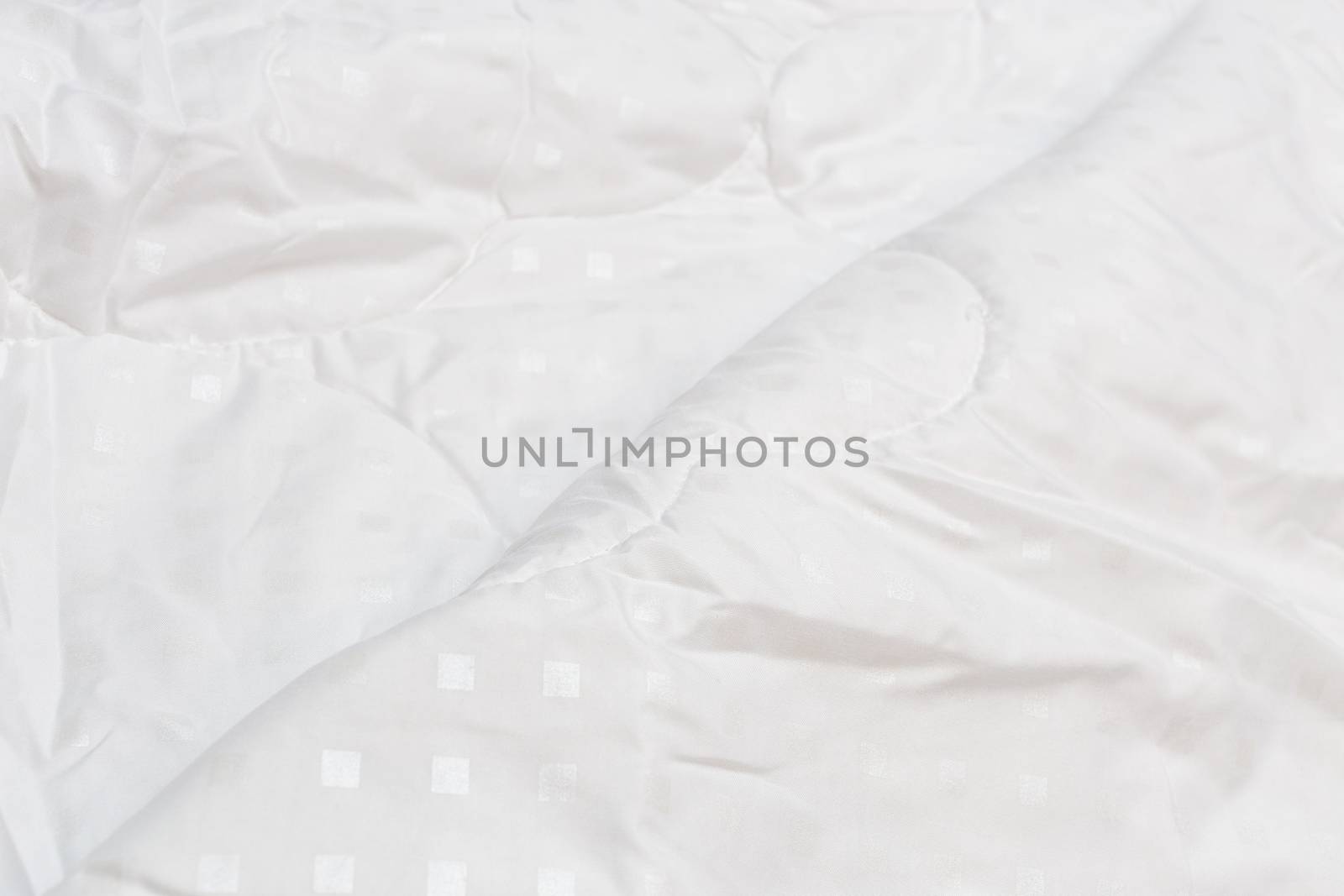 White fabric blanket close-up backdrop with selective focus and background blur. Small white squares pattern.