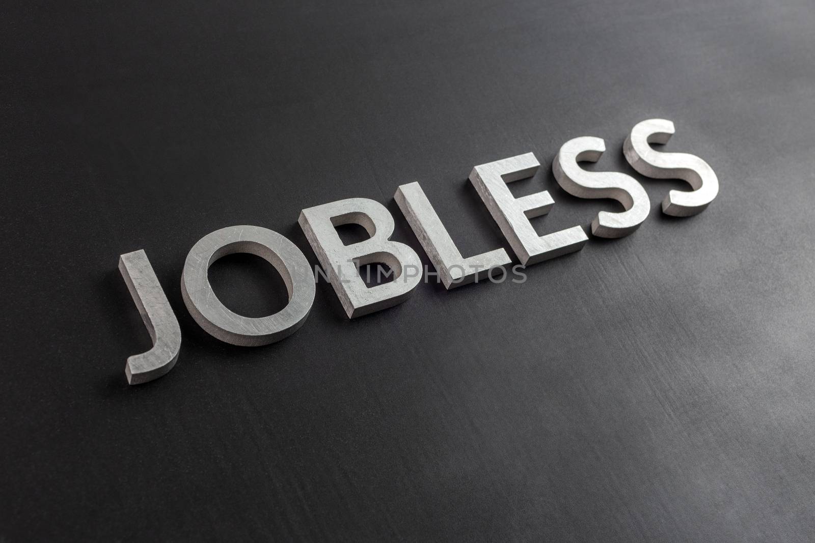 the word jobless laid with white scratched metal letters on flat black surface by z1b