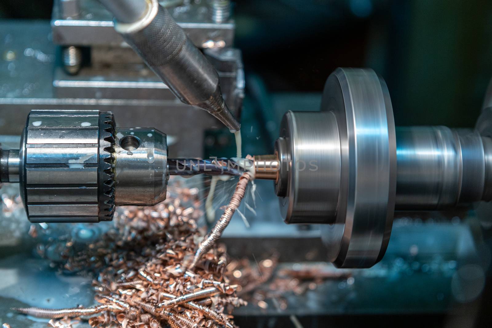 a process of brass drilling in lathe with liquid coolant - close-up with selective focus