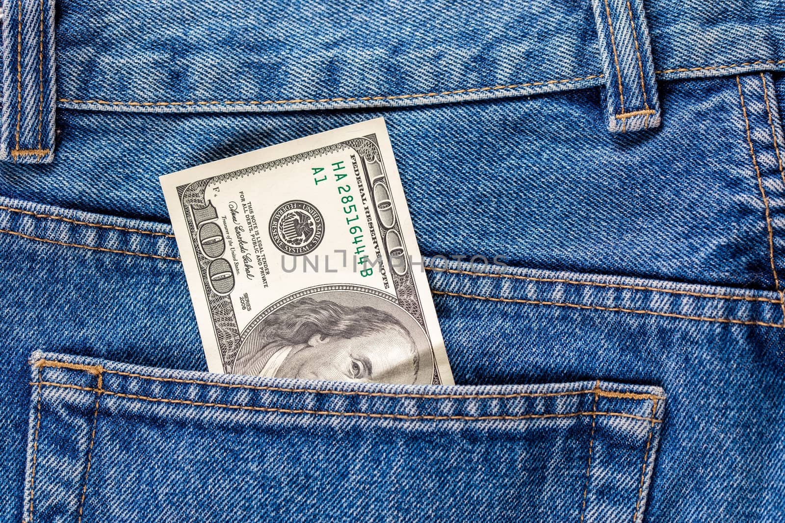 a hundred dollar banknote sticking out from rear jeans pocket - close-up.