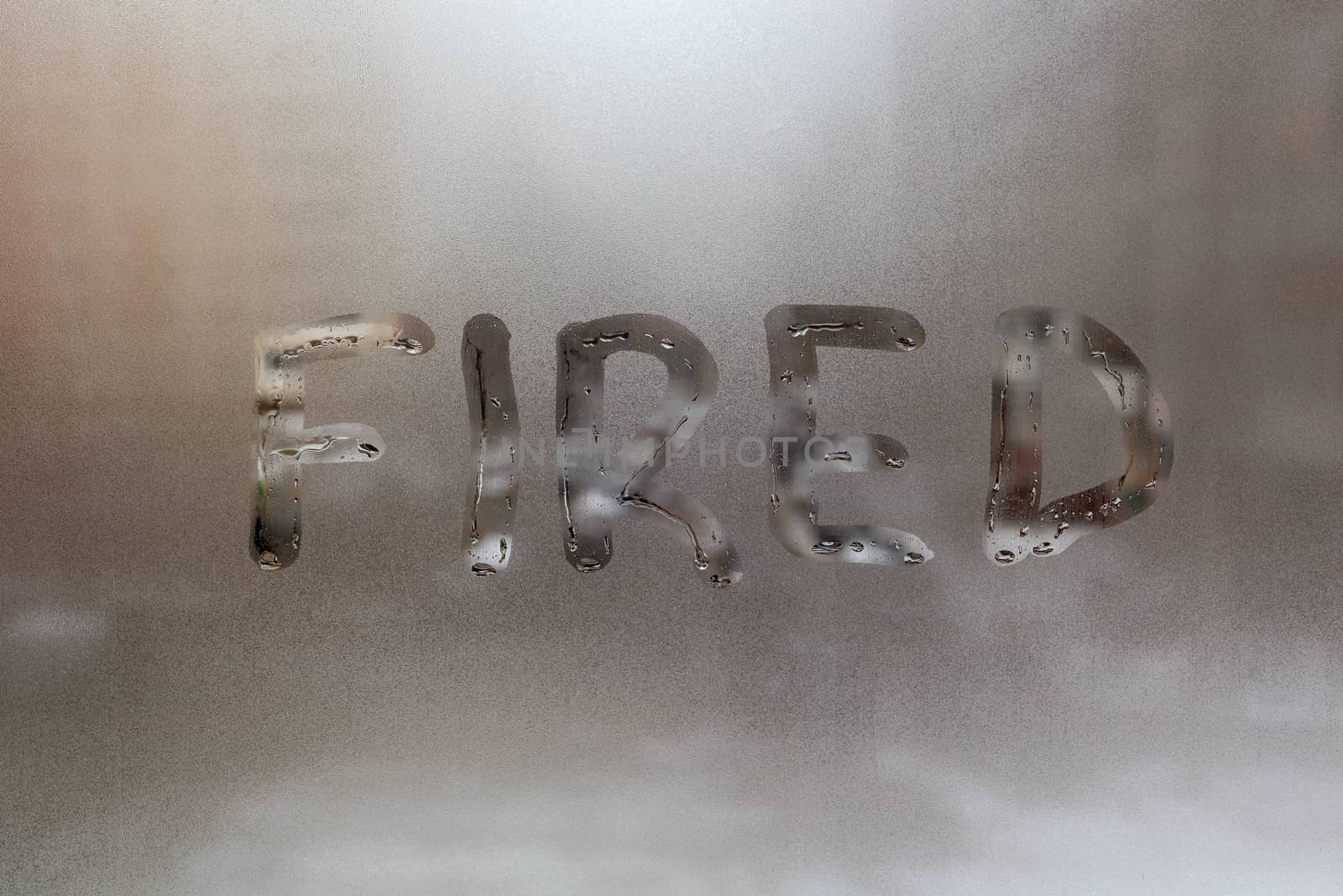 the word fired handritten on wet window glass at cloudy weather by z1b