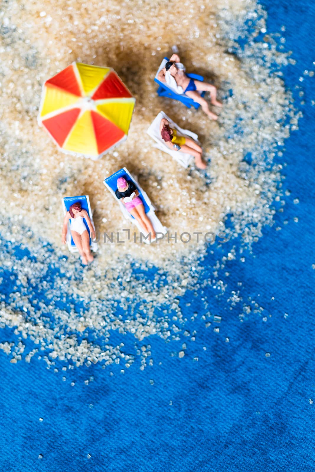 Miniature people sunbathing on The beach , Summer time concept by sirichaiyaymicro