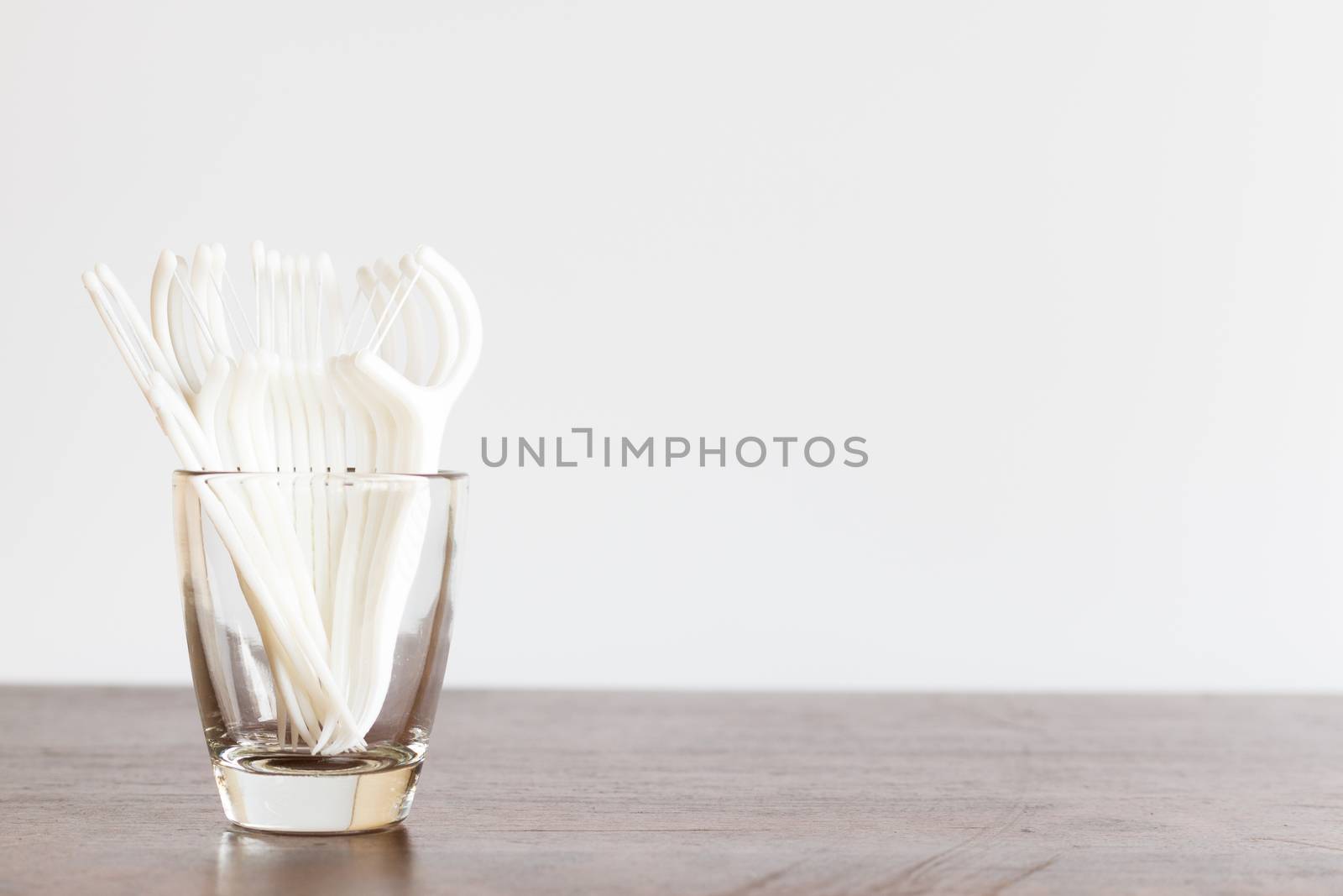 Oral Device : Dental floss in glass on wooden background by sirichaiyaymicro