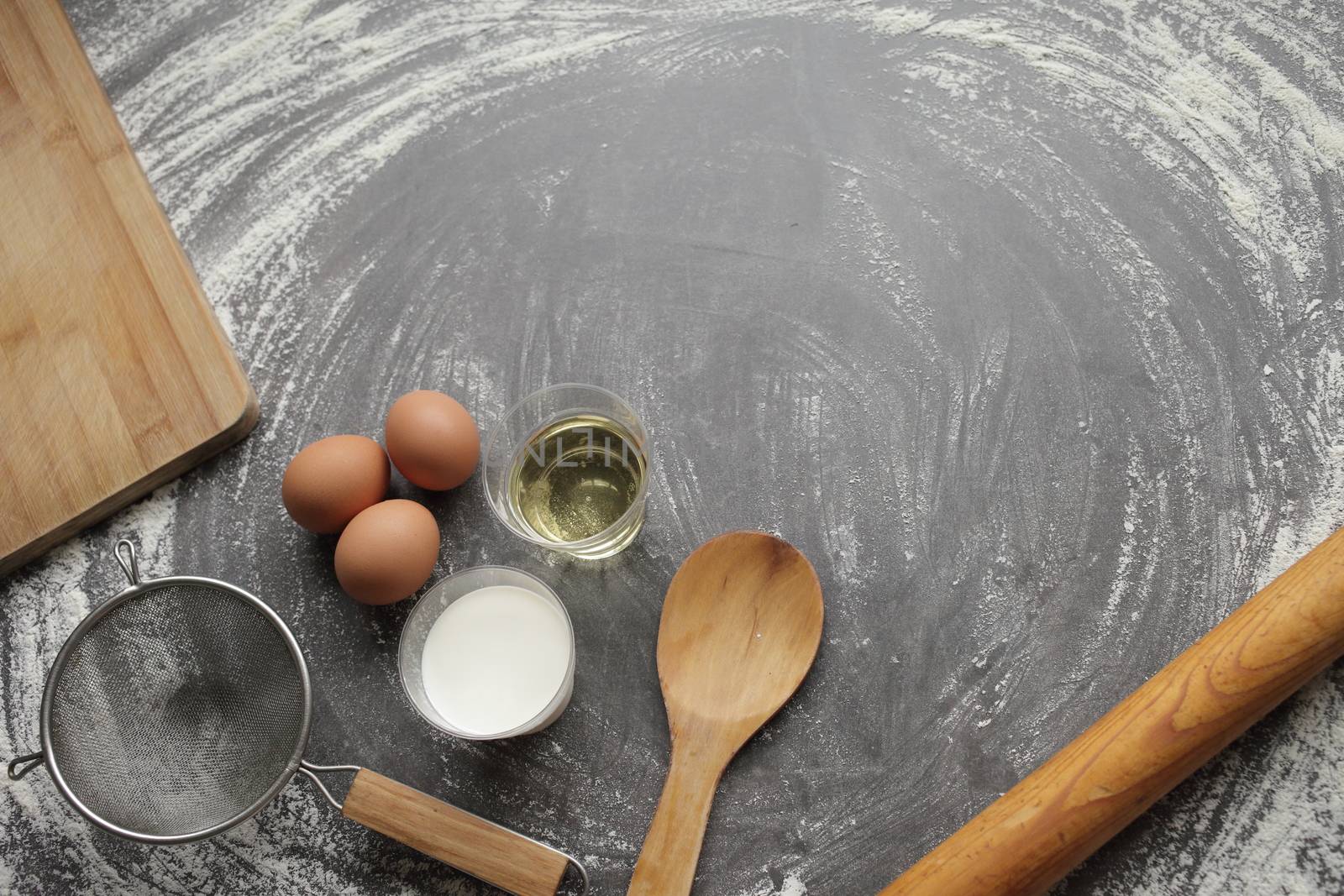 Chicken egg, flour, olive oil, milk, kitchen tool on gray table background. by selinsmo