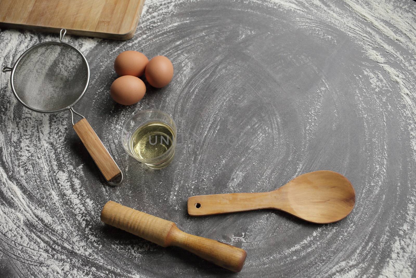 Chicken egg, flour, olive oil, kitchen tool on gray table background. Products by selinsmo