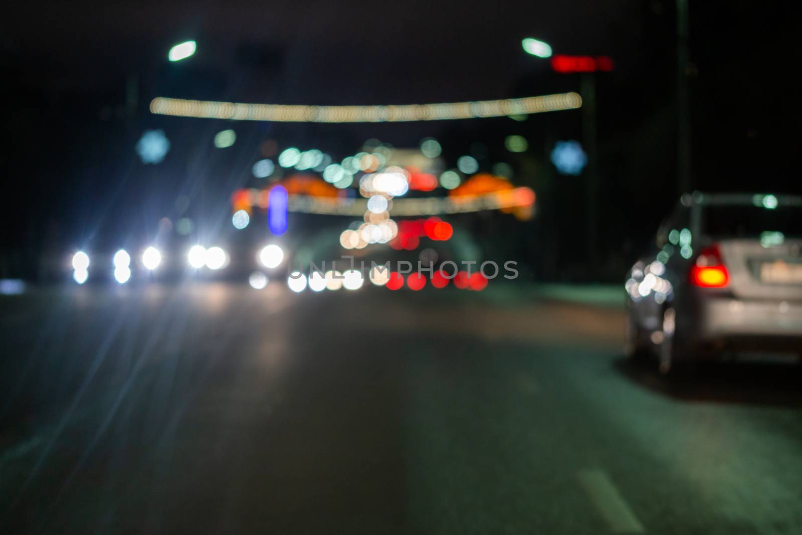 Defocused picture of night street car traffic - view from road. Colorful night life dark background.