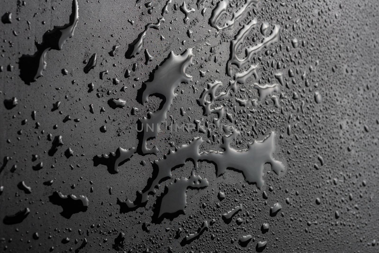 abstract background of wet black hydrophobic surface - close-up with selective focus and skewed perspective